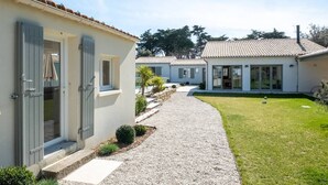 Une rangée de maisons modernes à un étage, dotées de volets gris, d’un chemin de gravier et d’une pelouse bien entretenue.
