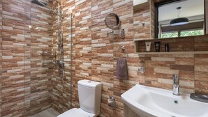 A modern bathroom with a shower, toilet, and sink, featuring a stone mosaic wall.