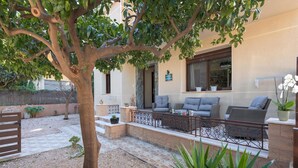 A courtyard with a tree, outdoor seating, a stone wall, and a building with a sign 'PARRO STUDIO'.