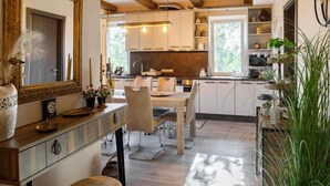 A modern kitchen with wooden beams, white cabinets, and a dining area with a table and chairs.