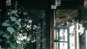 A rustic wooden building with a large window and a wooden cart outside. - Wine Space (Ambrolauri)