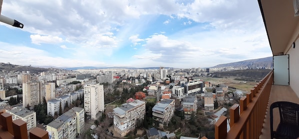 Un edifici alt amb múltiples pisos, balcons i vista a un paisatge urbà.