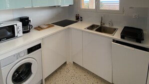 Una cocina compacta equipada con lavadora, microondas, cafetera y lavaplatos.