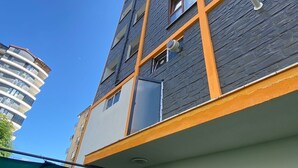 Edificio a più piani con un design architettonico moderno, caratterizzato da pannelli di colori scuri e chiari e tocchi arancioni.