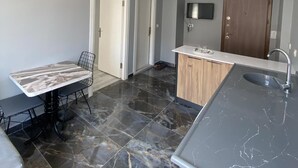 Una cucina moderna con un piano di lavoro in marmo, un'area pranzo con tavolo e sedie, e una lampada a sospensione.