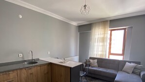 Una cucina moderna con isola in legno, lavello incassato e zona pranzo con divano grigio.