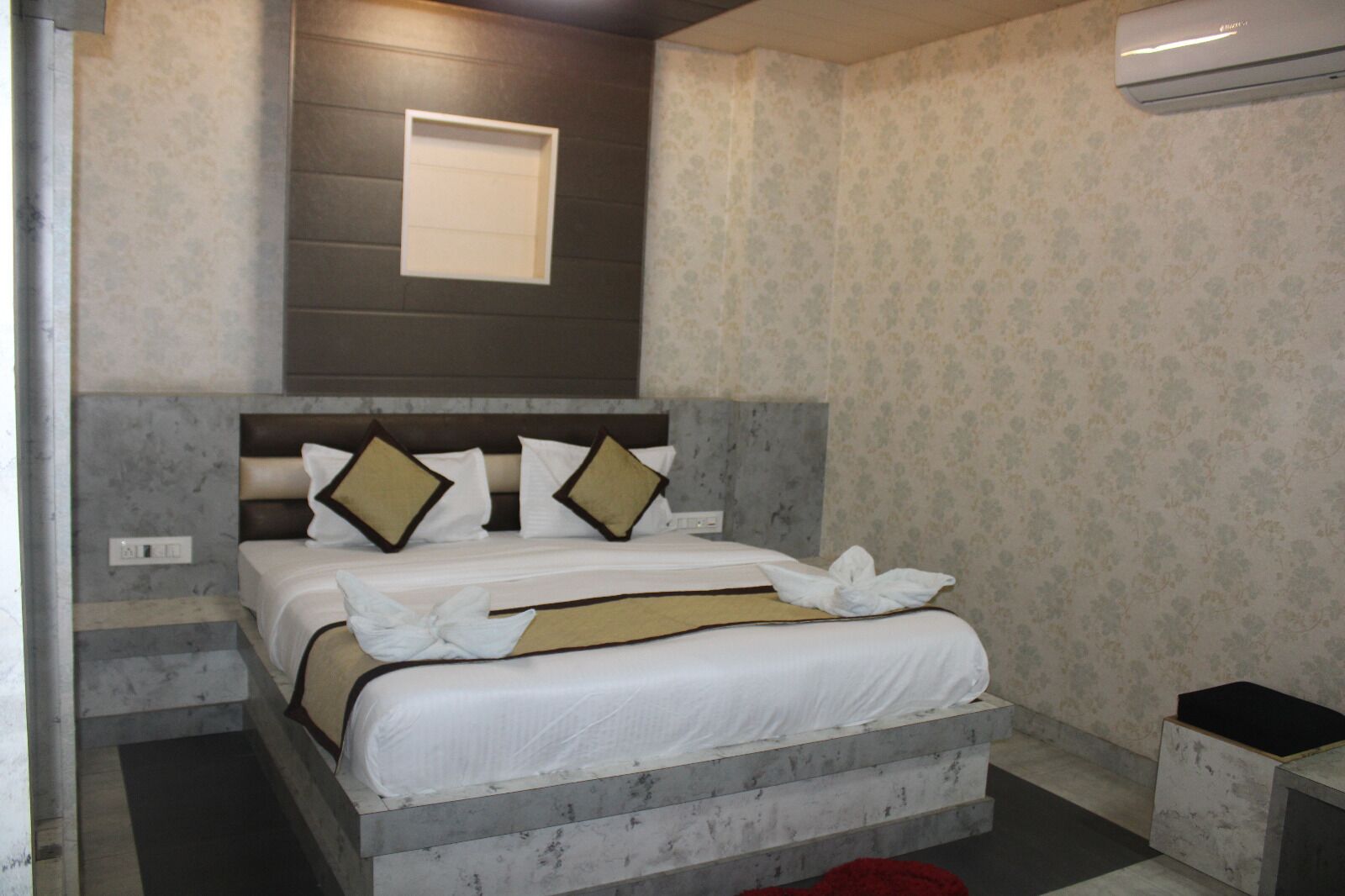 Un dormitorio con cama, cabecera, ventana y aire acondicionado de pared.