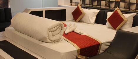 A modern bedroom with a curved bed, white bedding, and a patterned wall.