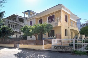 Ein zweistöckiges Gebäude mit Balkon, geschlossenem Eingangsbereich und einer Treppe, die zu der oberen Etage führt.