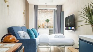 Ein Hotelzimmer mit Bett, Schreibtisch, Stuhl, Fernseher und Blick ins Freie.