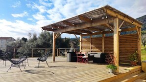 Eine Holzterrasse mit Sitzgelegenheiten im Freien, einer Pergola und Kübelpflanzen.