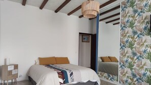Ein Schlafzimmer mit einem Bett, einem Nachttisch, einem Spiegel und einer Holzzieldecke.
