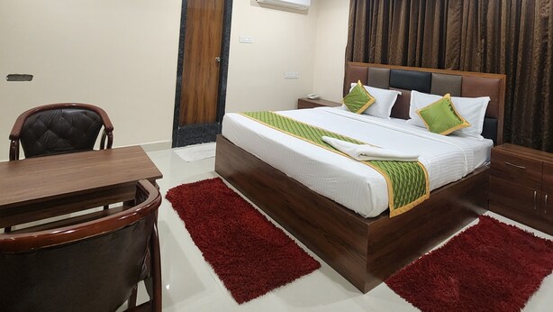 A hotel room with a bed, a desk, a chair, a ceiling fan, and an air conditioning unit. - Hotel Ocean View Vizag (Visakhapatnam)