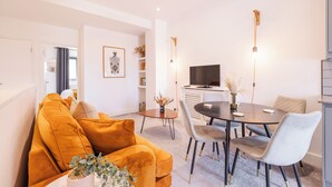 Een moderne woonkamer met een bank, eettafel, stoelen en een televisie.