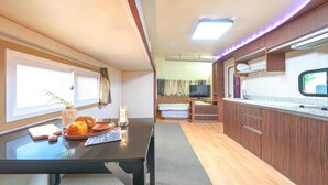 Interior de una caravana compacta con zona de comedor, kitchenette y cama.