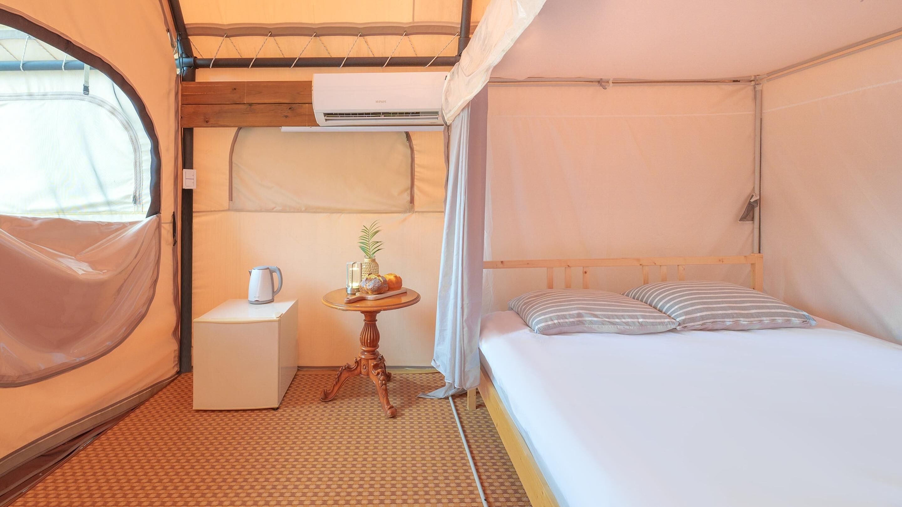 Una habitación compacta con una cama, una mesita con un hervidor y una ventana con vistas.