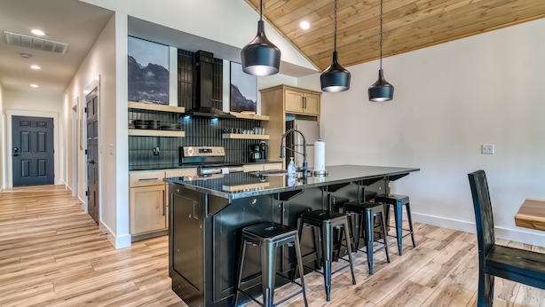 Une cuisine moderne dotée d’un îlot central, de tabourets de bar et de luminaires suspendus.