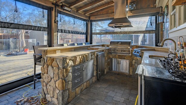 Una cocina con isla de piedra, electrodomésticos de acero inoxidable y vista al patio trasero.