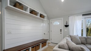 Una sala de estar con un banco empotrado, cestos de mimbre y un sofá gris.