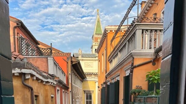Une rue étroite bordée de bâtiments des deux côtés, une vue à travers une fenêtre et un plateau de nourriture.