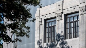 Fachada de edificio con grandes ventanales y detalles de piedra decorativa.