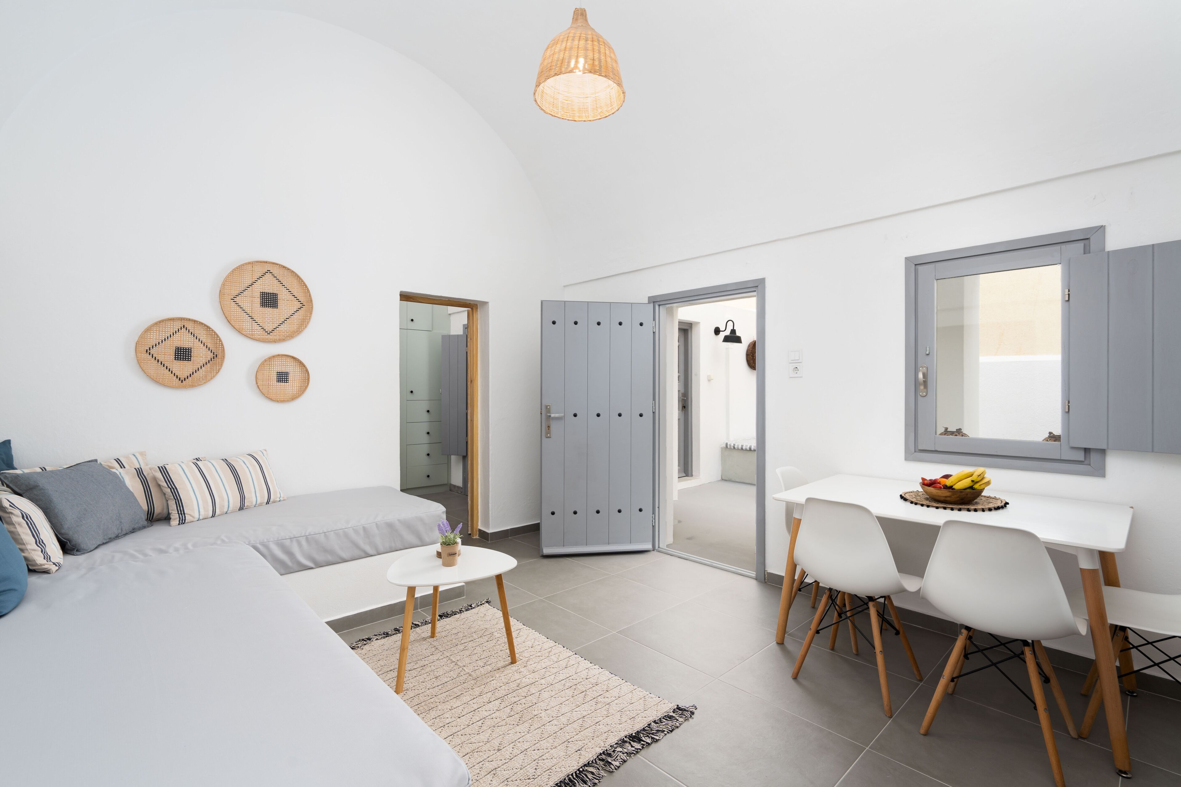 A modern bedroom with a bed, a desk, and chairs. There are lockers and a door leading to another room.