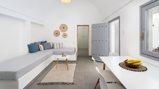 Un espacio habitable moderno y funcional con sofá, mesa de comedor y área de cocina.