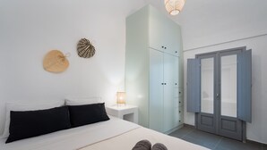 Un dormitorio con cama, mesita de noche, armario y puerta.