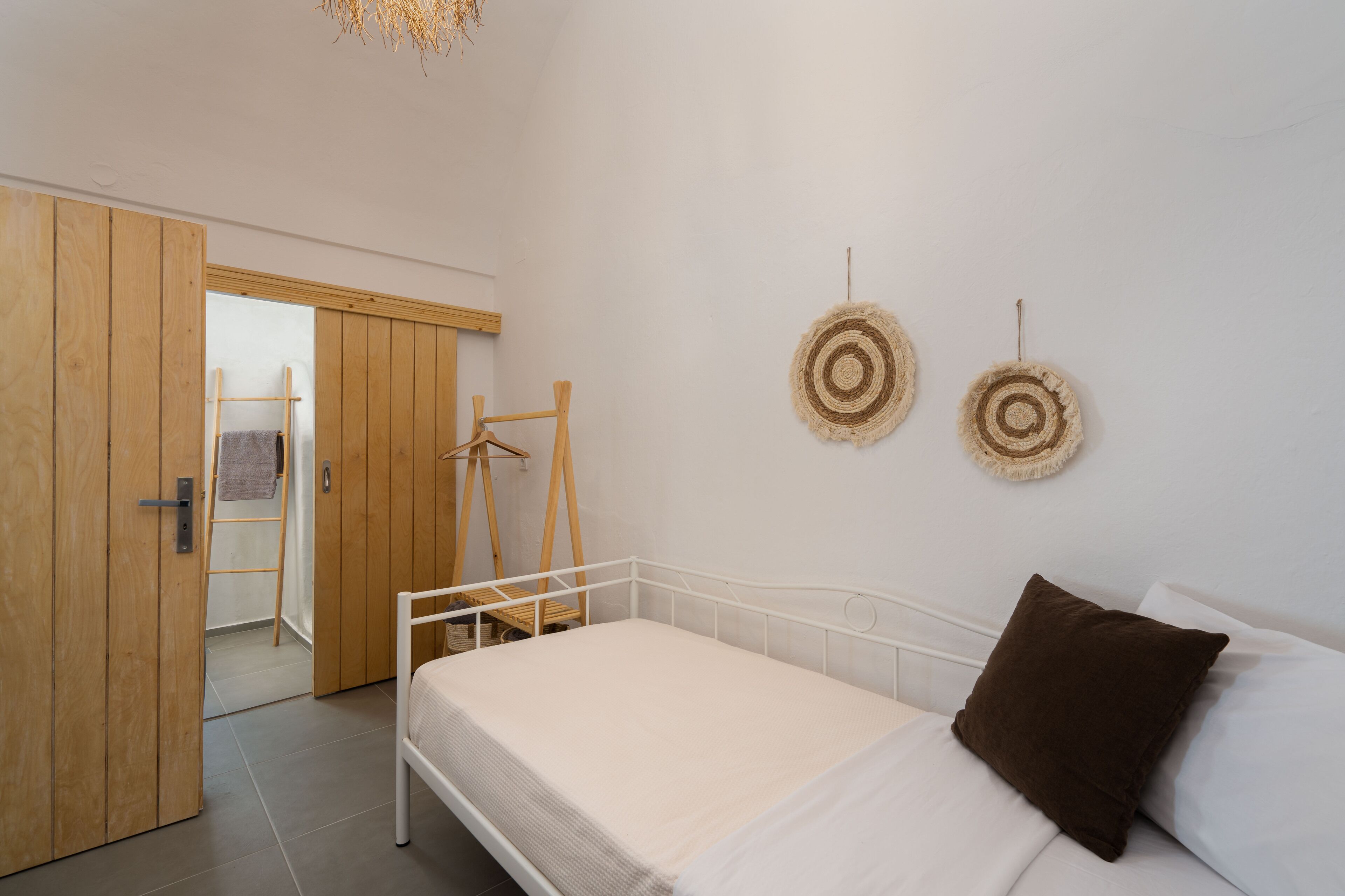 A bedroom with a bed, wooden wardrobe, and two wall-mounted circular decorations.