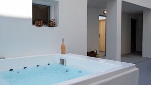 Un baño moderno con una bañera grande, una ventana pequeña y una puerta de madera.
