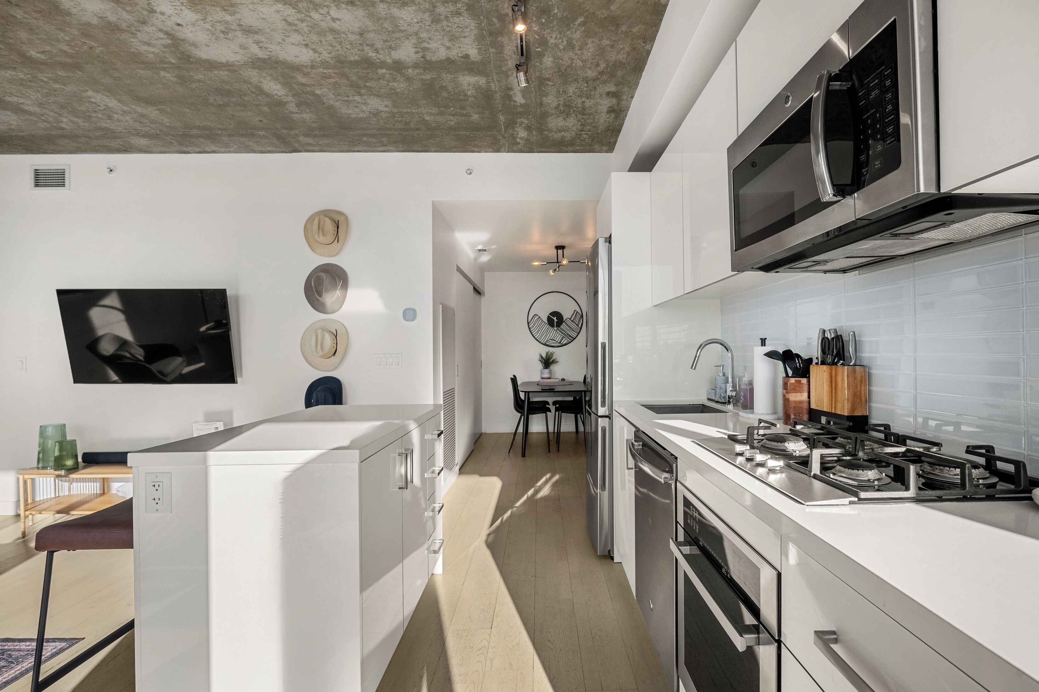 Una cocina moderna con armarios blancos, un microondas integrado y una estufa a gas.