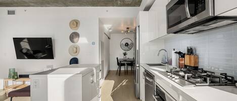 Una cocina moderna con armarios blancos, un microondas integrado y una estufa a gas.