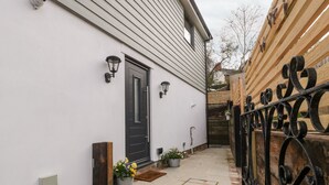A house with a black door, a small front porch, and a wooden fence. - Sevenwoods View (Longhope)