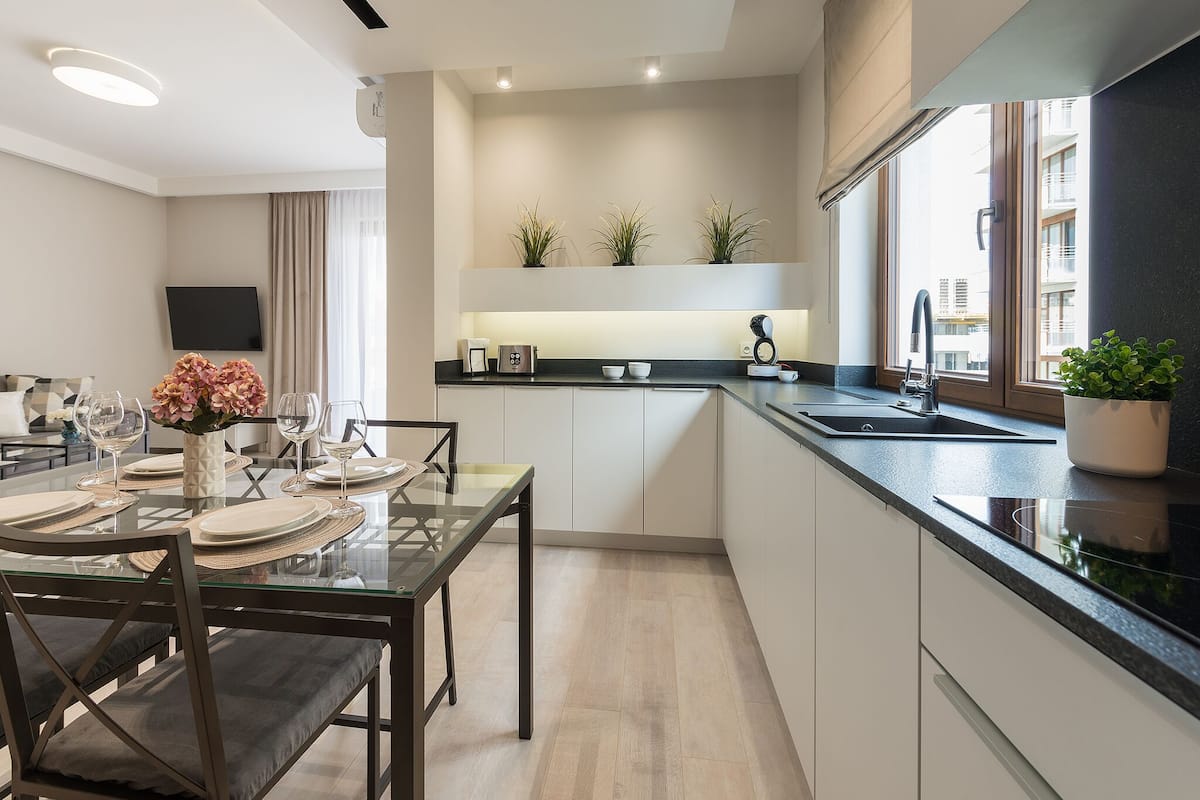 A modern kitchen with a dining area, built-in appliances, and potted plants.