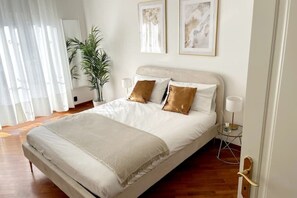 A neatly arranged bedroom with a bed, bedside lamps, and a potted plant. - Fantastic apartment with a terrace (Milano)