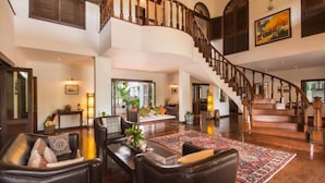 A spacious living area with a large staircase, leather sofas, and a patterned rug.
