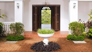 A building with a balcony, an arched entrance, and a central planter with greenery.