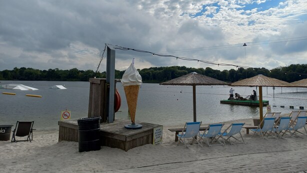 A beachside setting with a large ice cream cone, beach chairs, umbrellas, and a wooden deck.