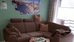 A living room with a brown sofa, a small wooden coffee table, and a painting on the wall.