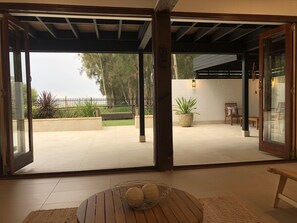 An open patio with a view of a garden, a wooden table with a bowl, and a potted plant. - The COCO - (Berkeley Vale)
