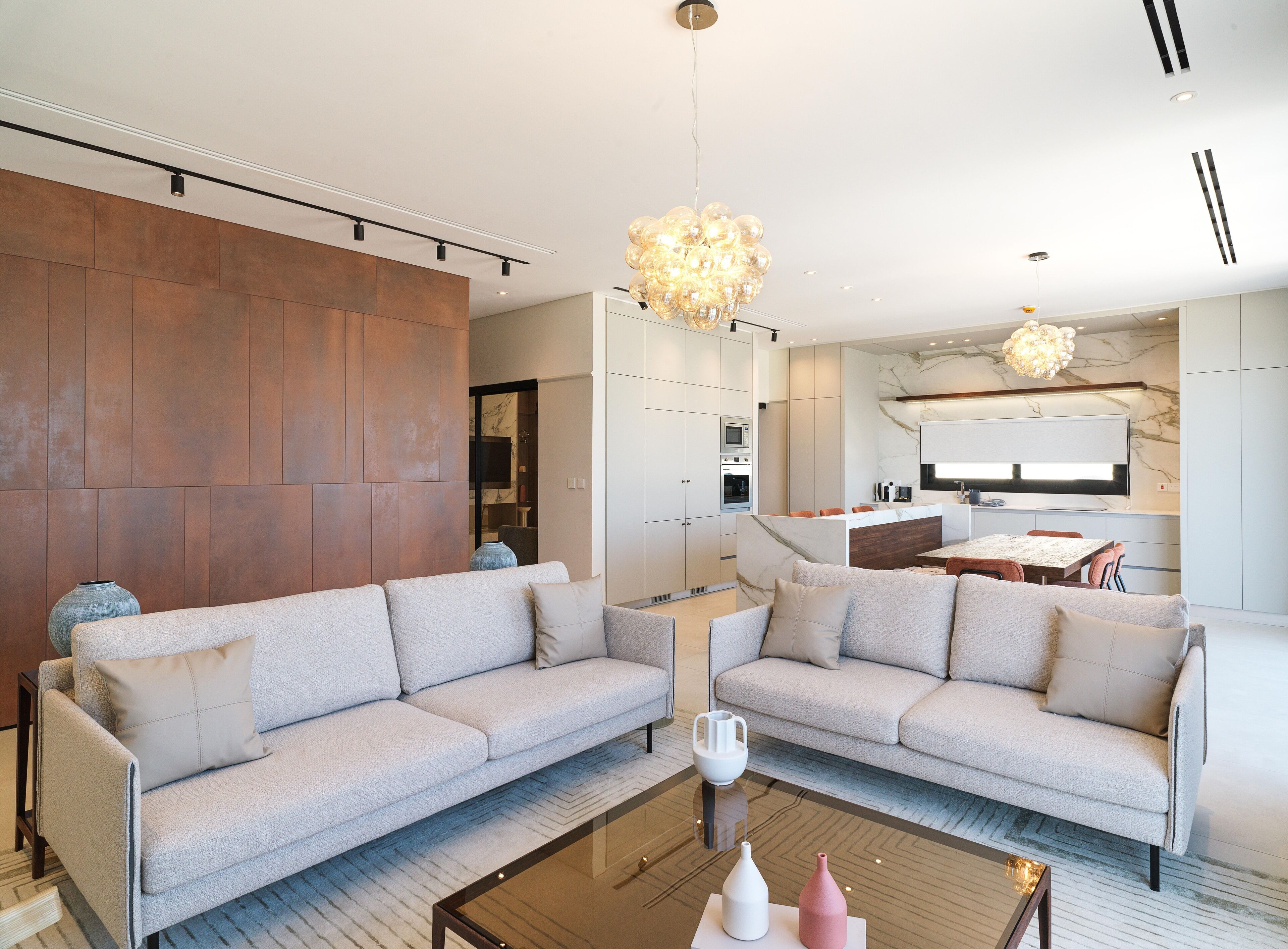 A modern living room with two sofas, a coffee table, and a kitchen in the background.