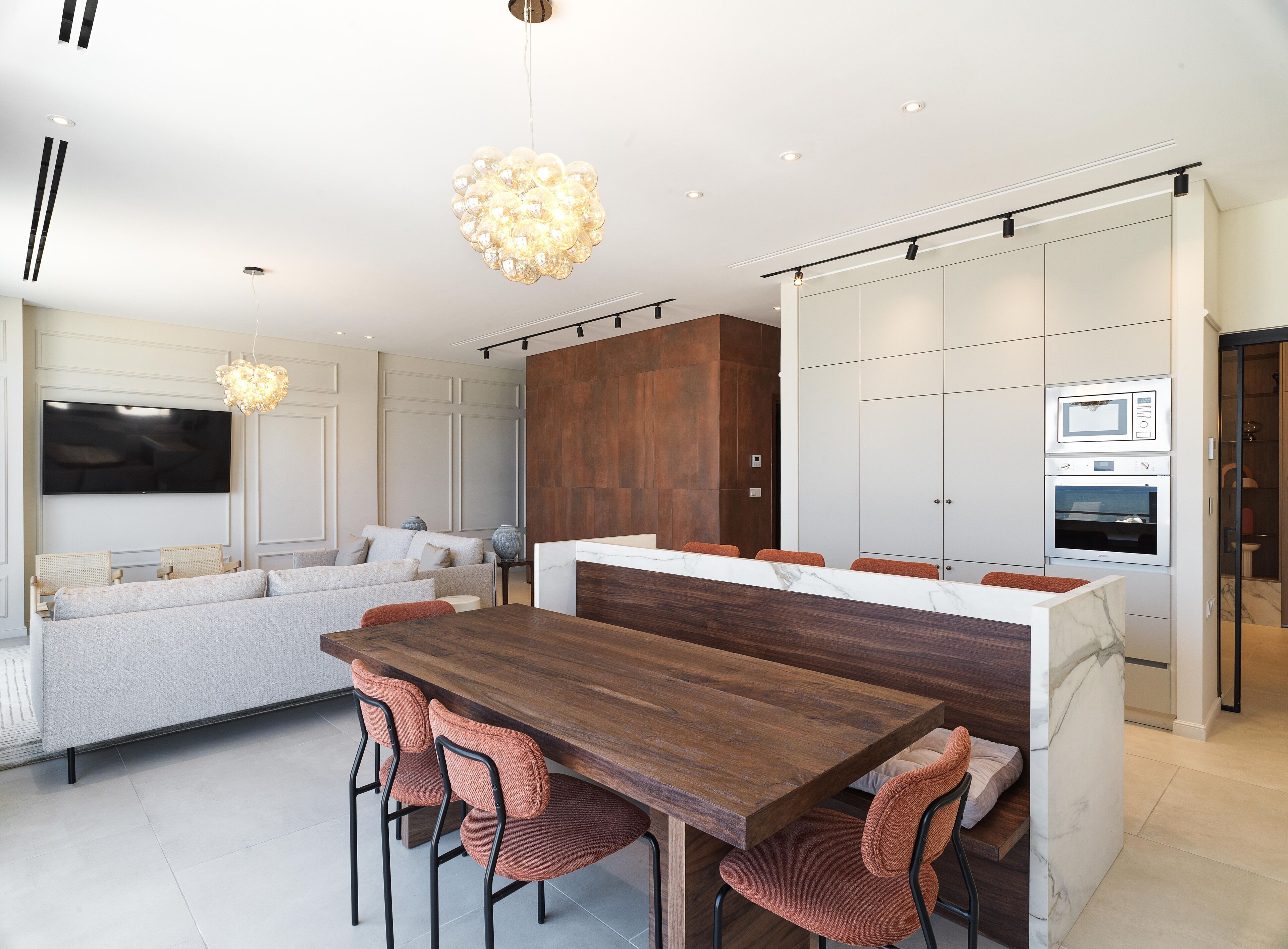 A modern kitchen with a wooden island, built-in appliances, and a seating area with a sofa and chairs.