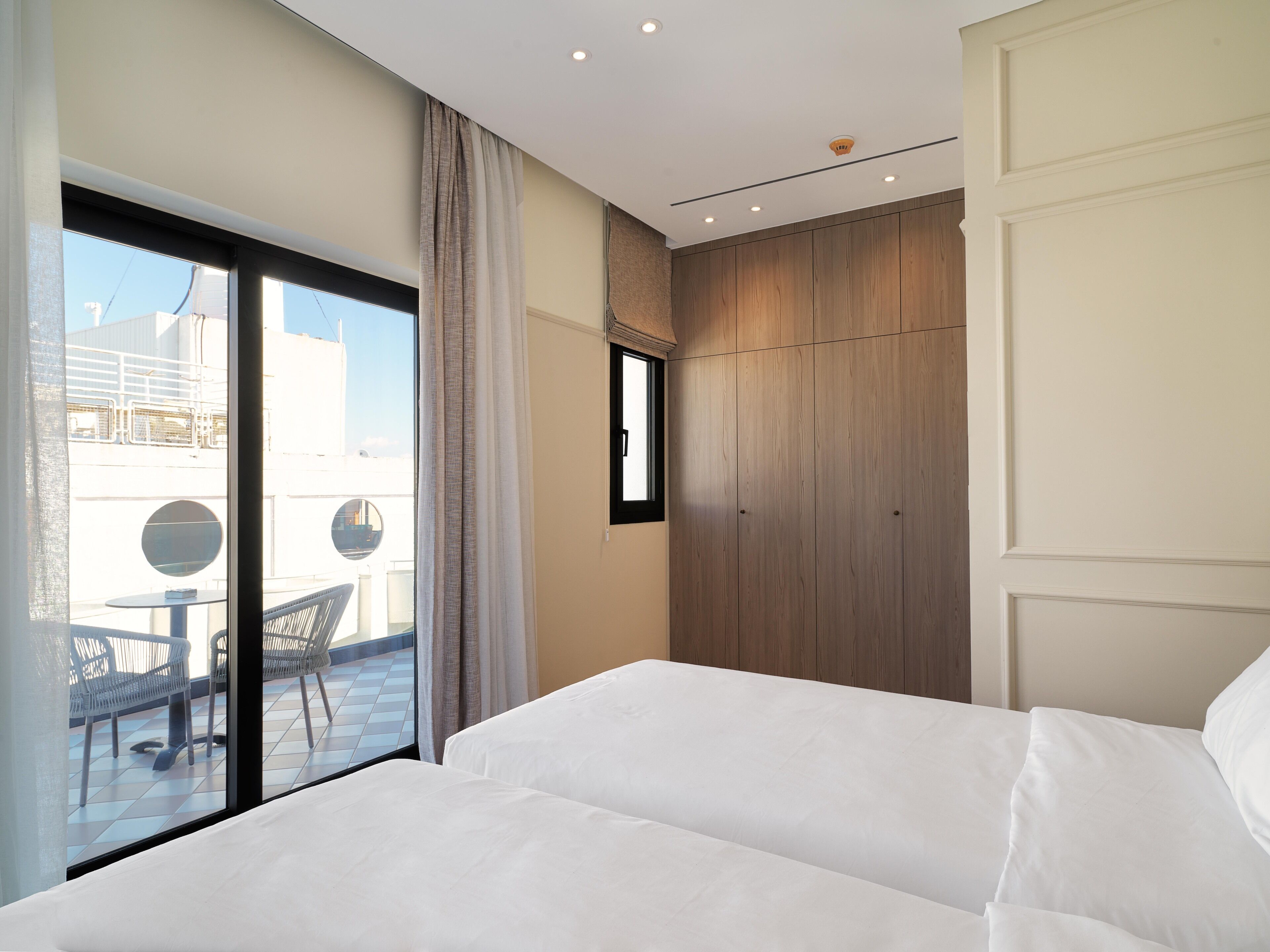 Habitación de hotel con un amplio ventanal corredero que da a una zona de estar exterior.