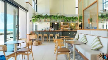 Un café moderno con mobiliario de madera, una zona de bar y vistas al océano.