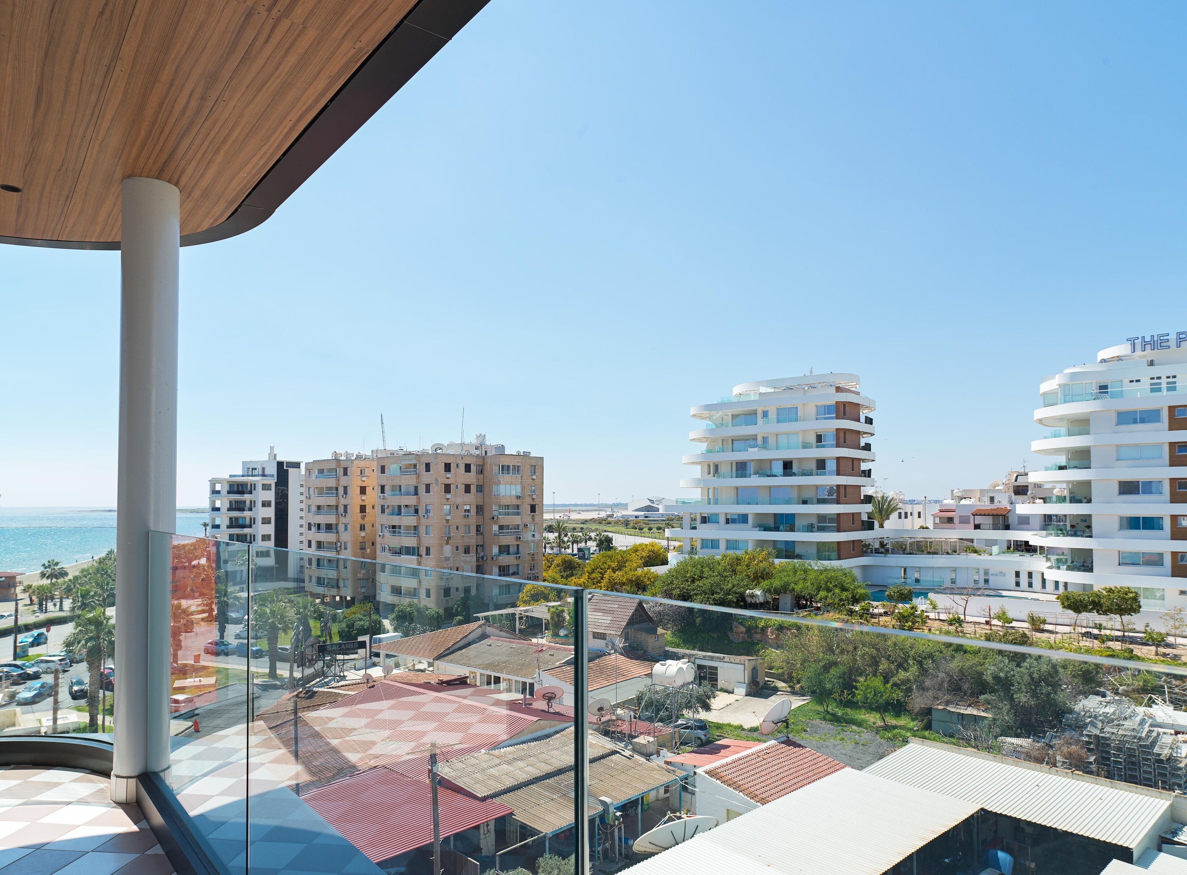 A modern building with multiple floors, large windows, and a view of the sea.