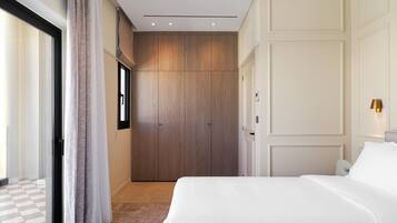 A bedroom with a large bed, a wardrobe, and a sliding door leading to a balcony.