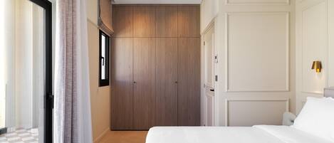 A bedroom with a large bed, a wardrobe, and a sliding door leading to a balcony.