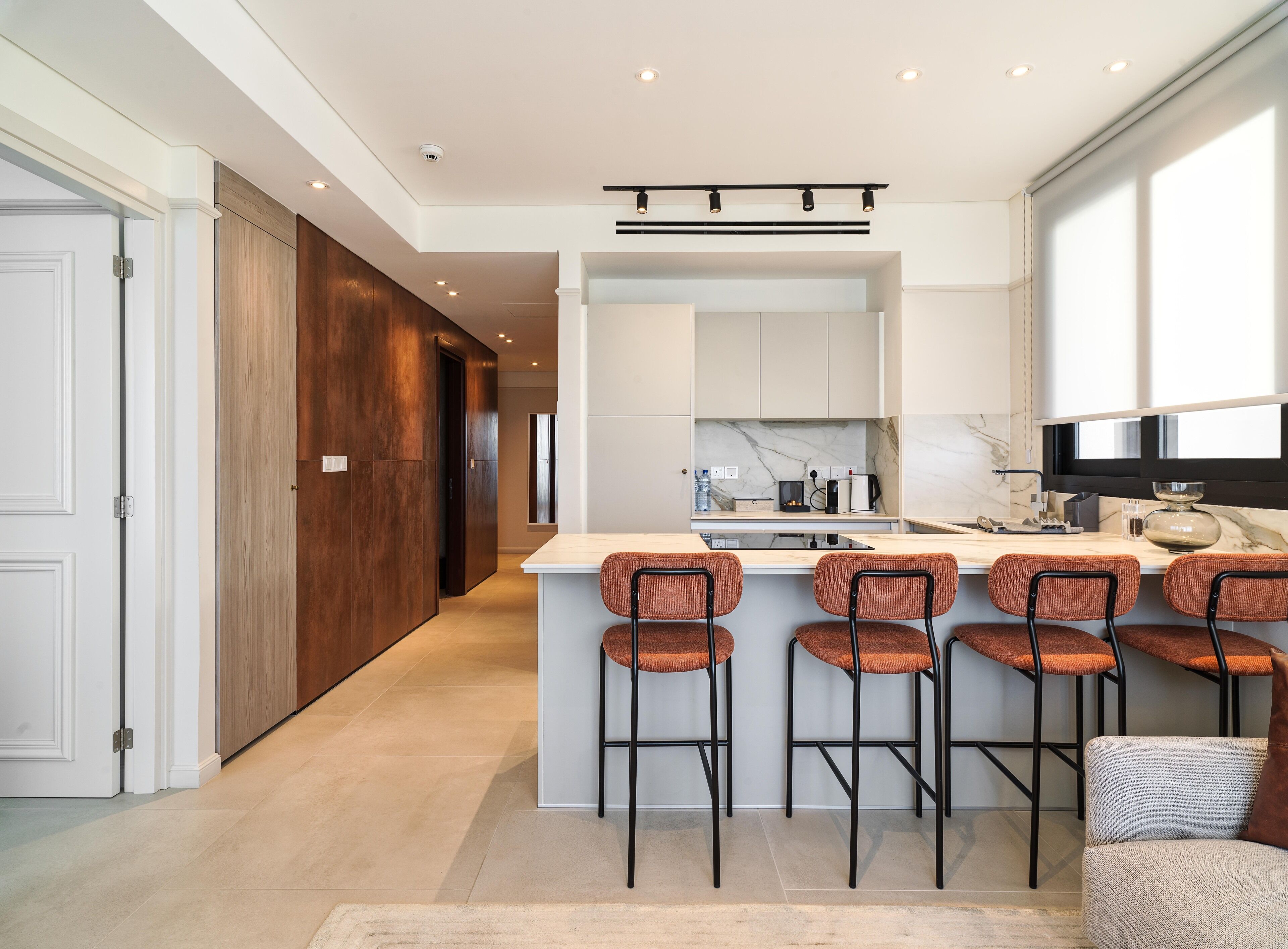 A modern kitchen with a central island, bar stools, and a seating area with a sofa.