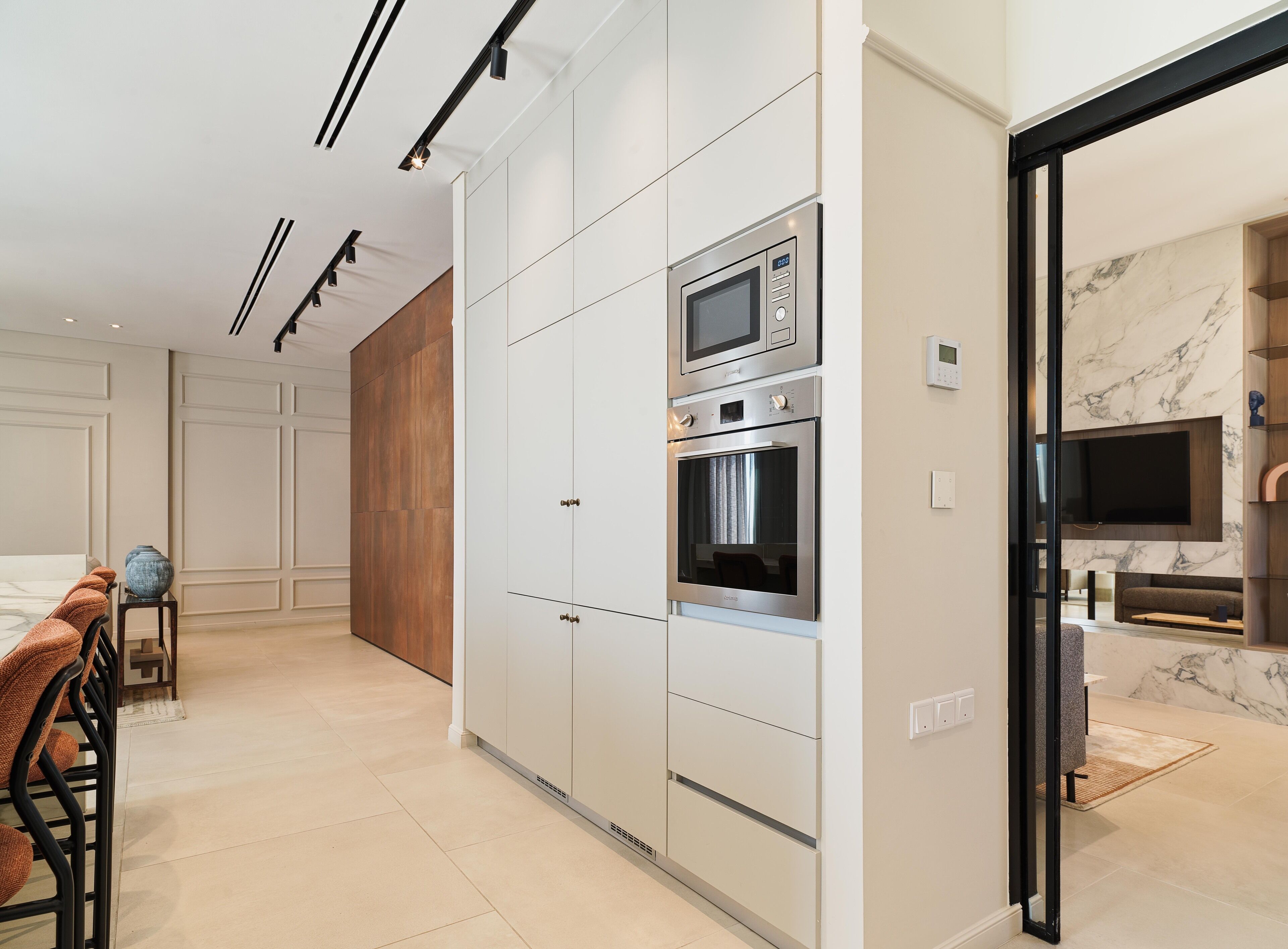 A modern kitchen with built-in appliances, a dining area with a table and chairs, and a living area with a TV and seating.