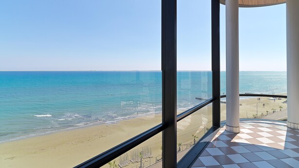 A balcony with a view of the beach and ocean.
